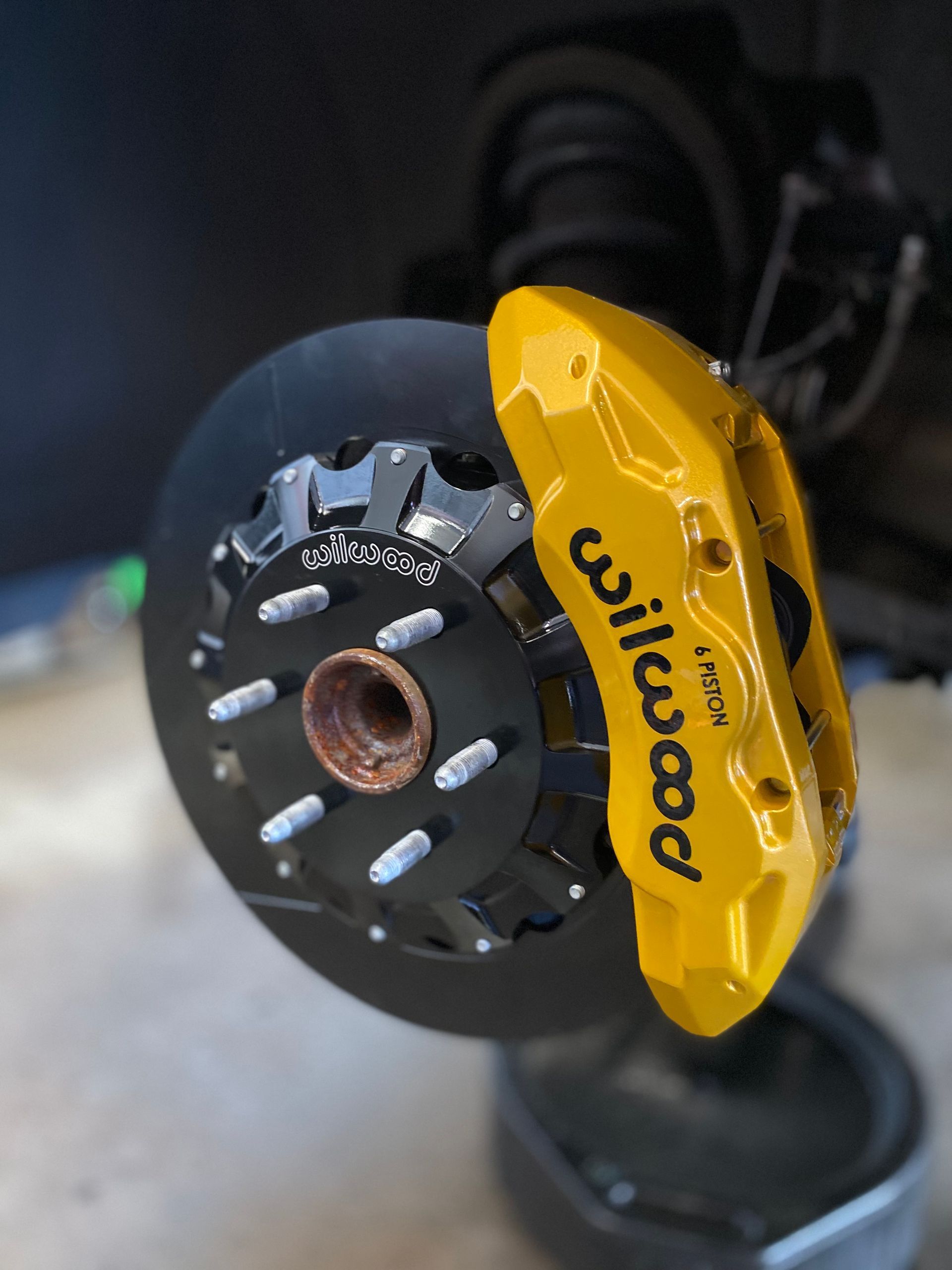 A close up of a yellow wilwood brake caliper