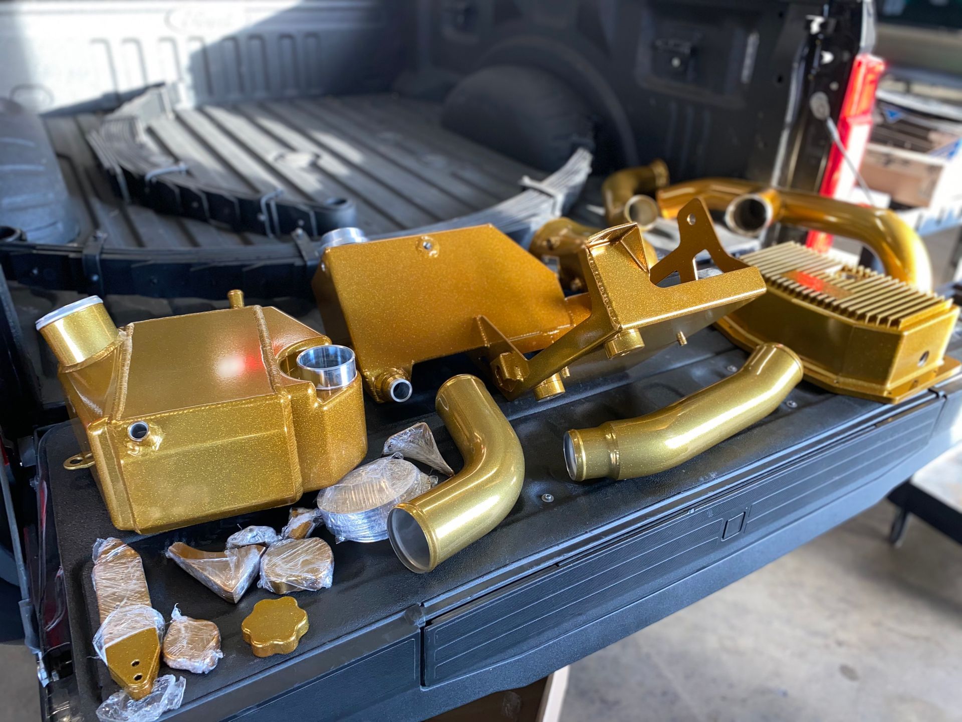 A bunch of gold parts are sitting on the back of a truck.