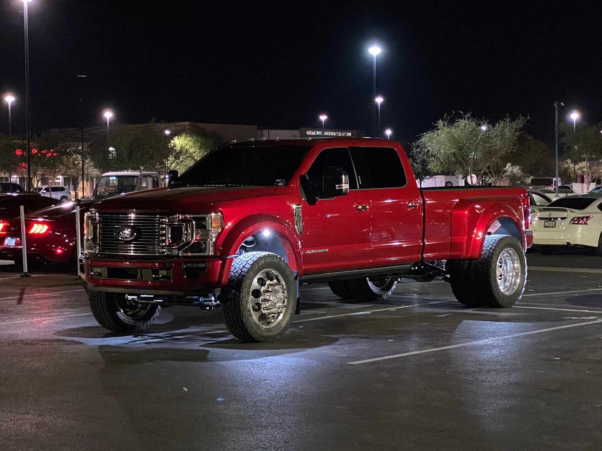 A red truck is parked in a parking lot at night.