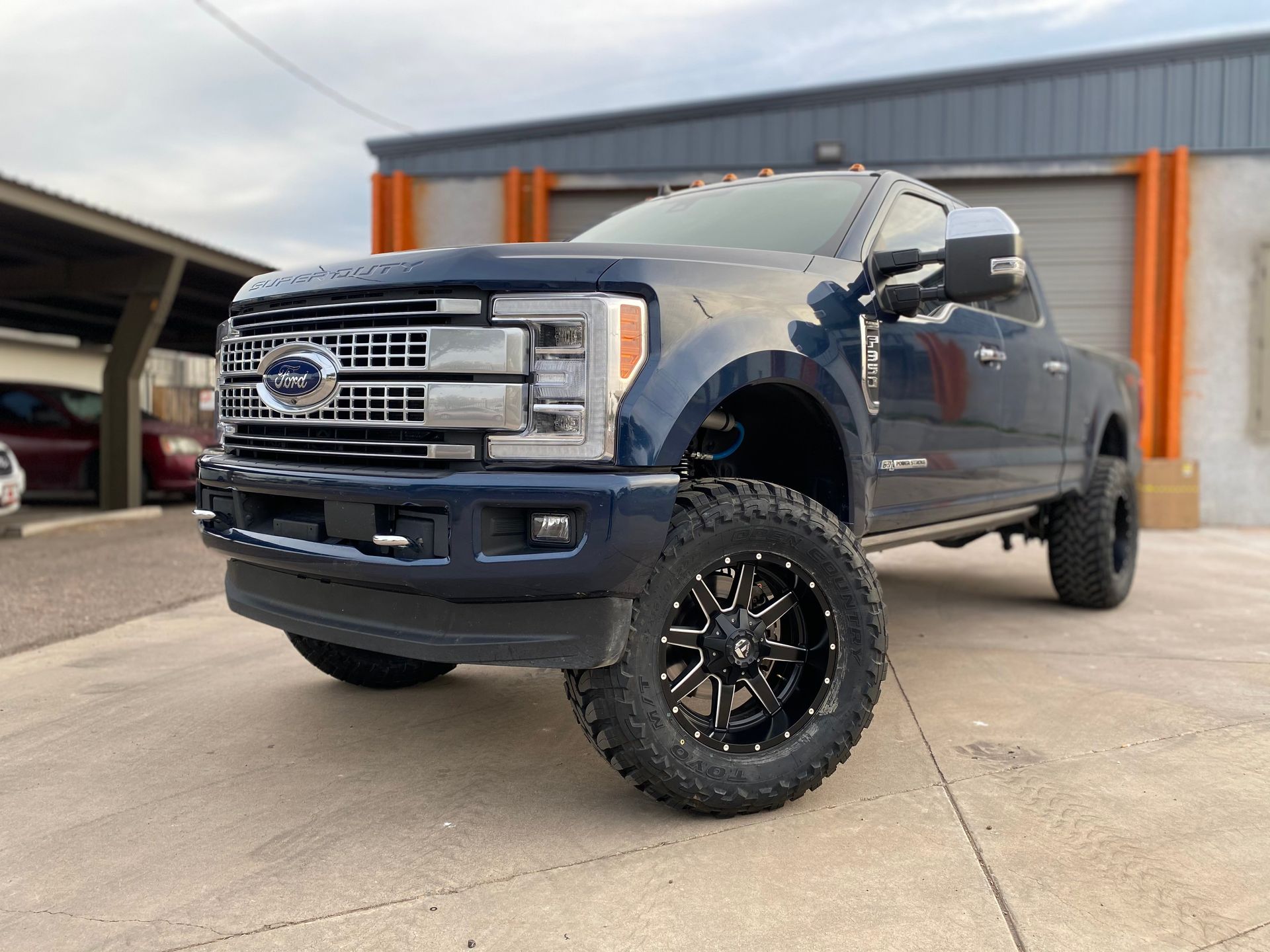A blue ford truck is parked in front of a building.