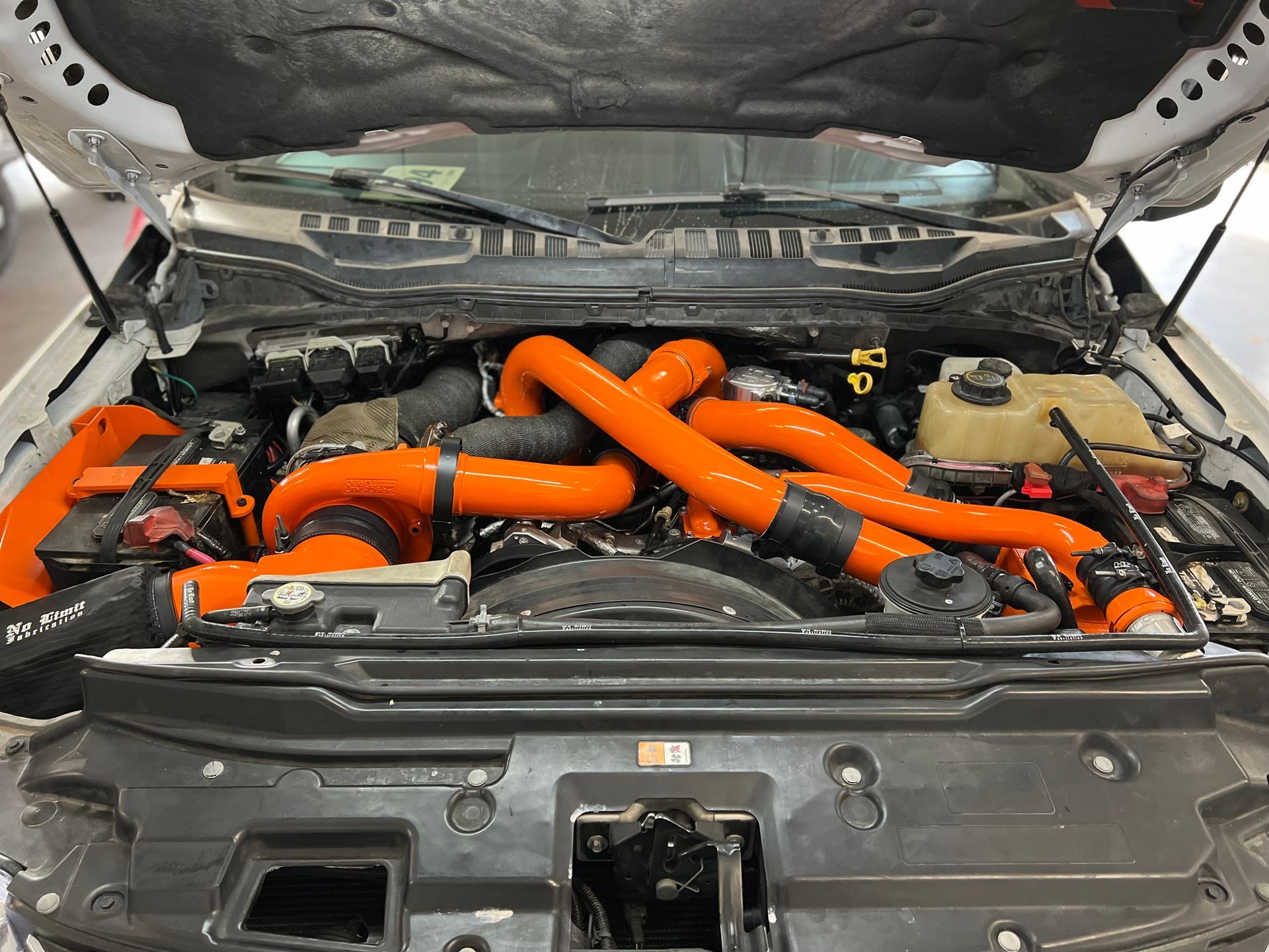 The engine of a car with the hood open and orange hoses coming out of it.