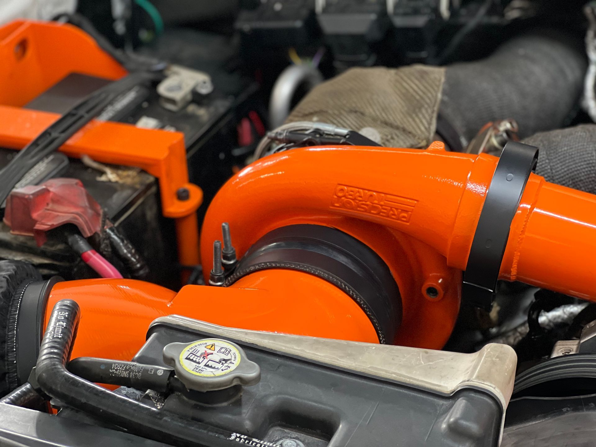 A close up of a car engine with an orange turbocharger