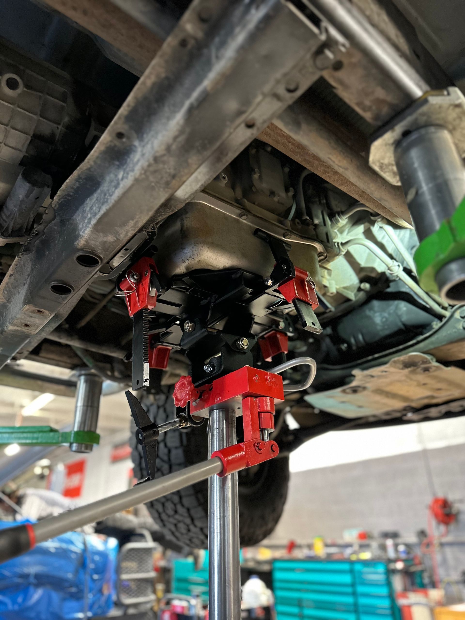 The underside of a car is being worked on in a garage.
