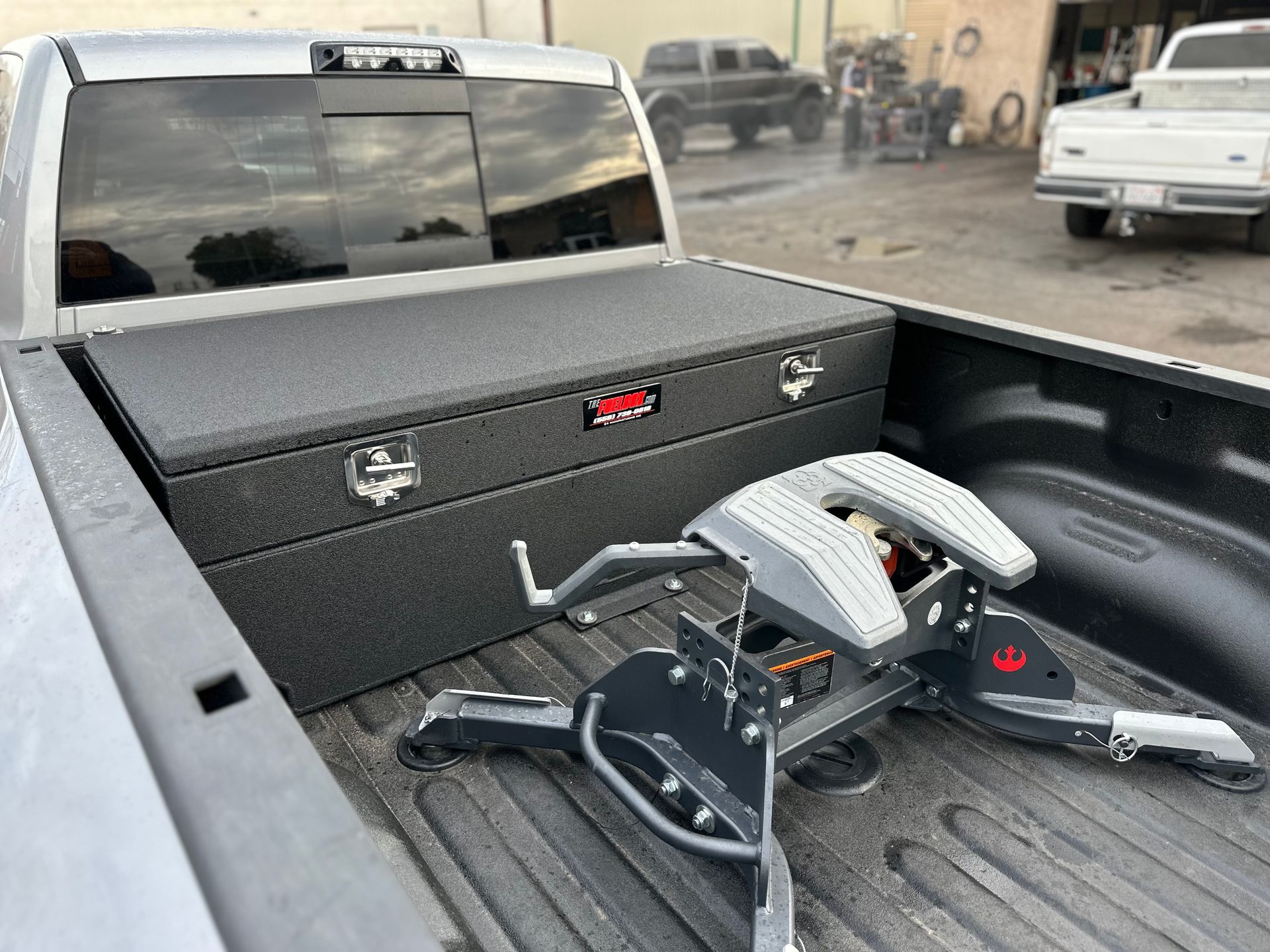 The back of a truck with a toolbox and a trailer hitch.