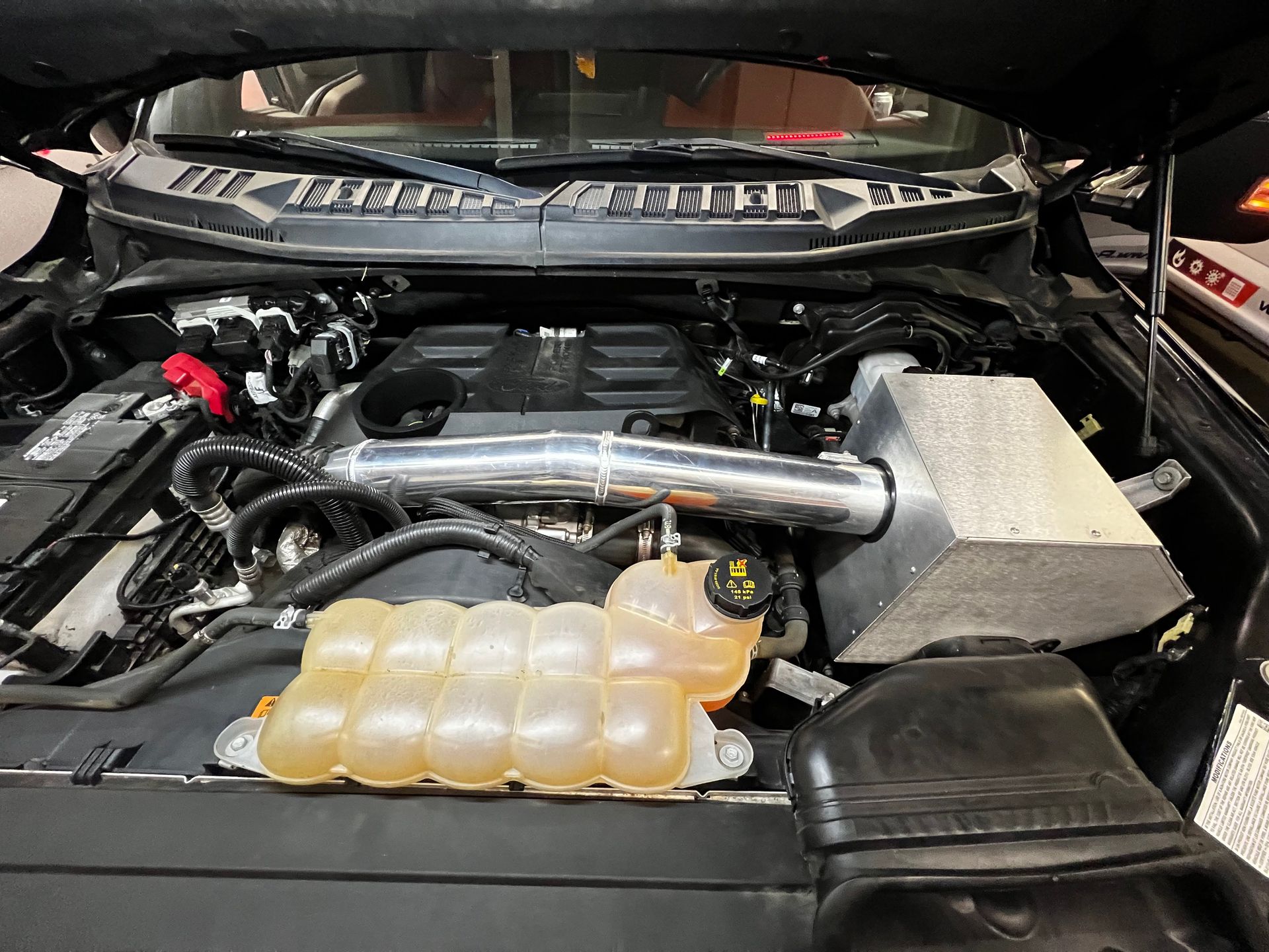 A close up of the engine of a car with the hood open.