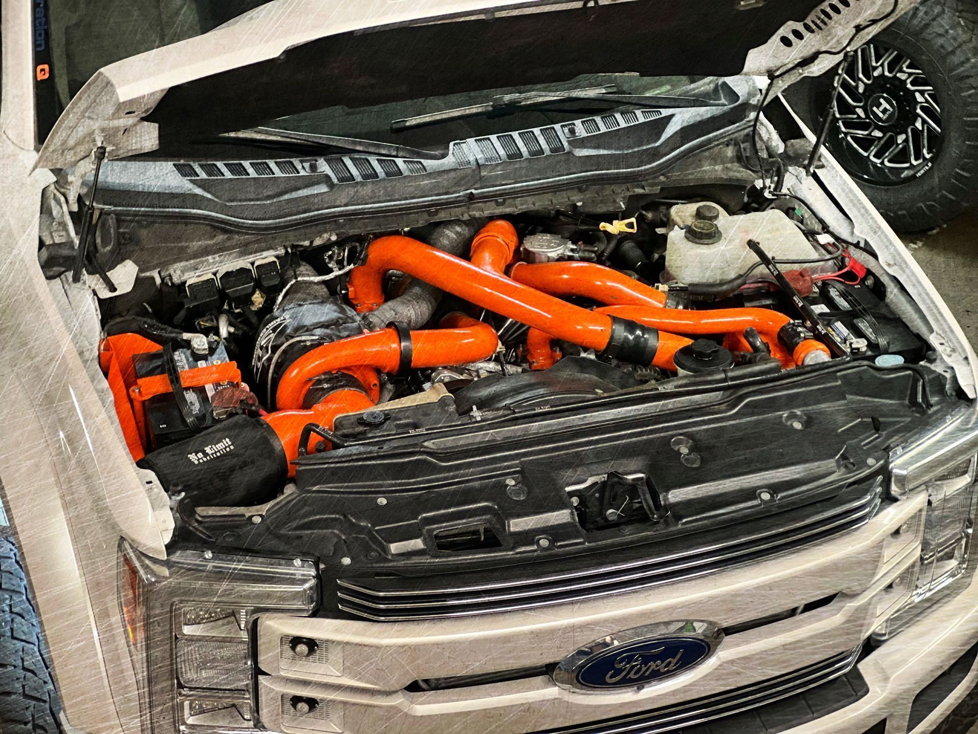 The hood of a white ford truck with orange hose attached to it.