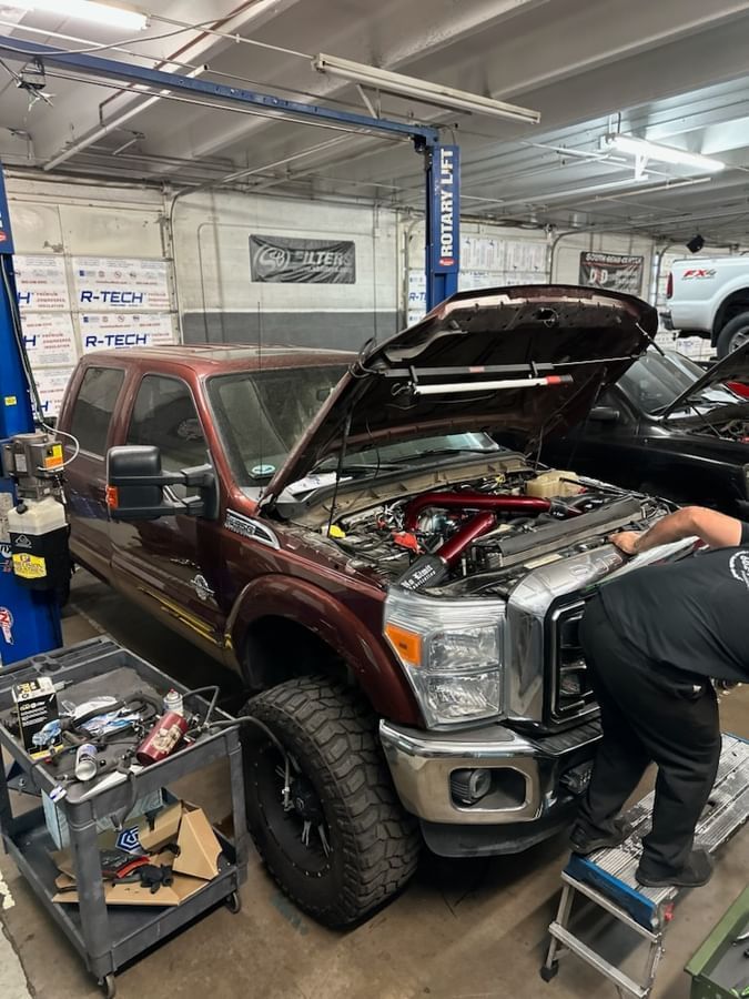 A man is working on the engine of a truck in a garage.