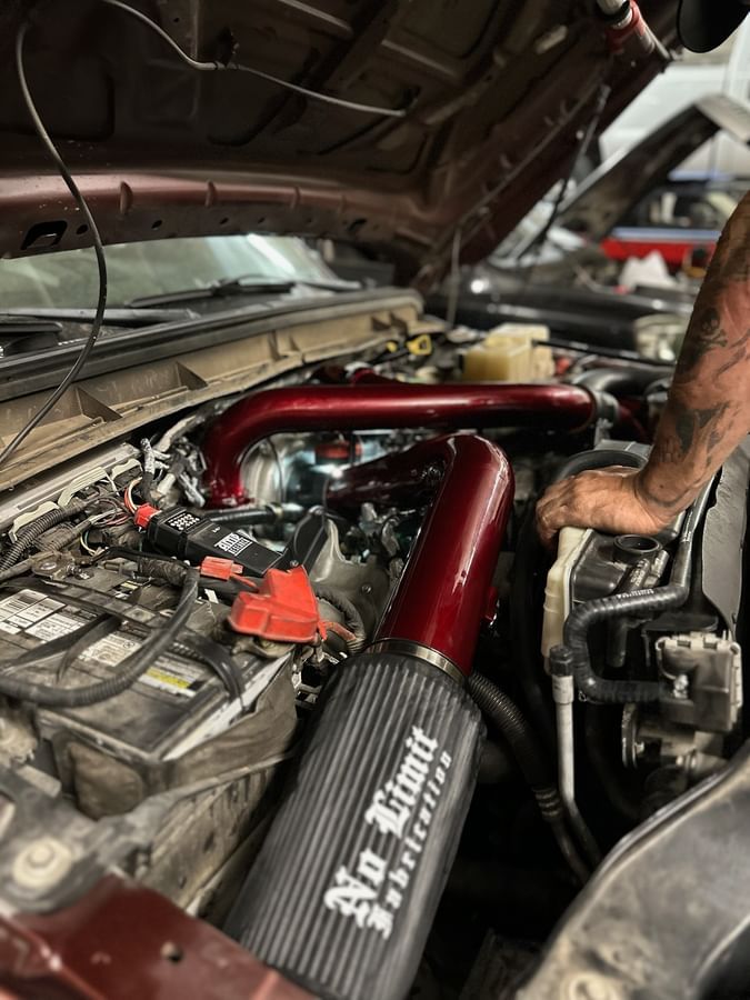 A man is working on the engine of a car with the hood open.