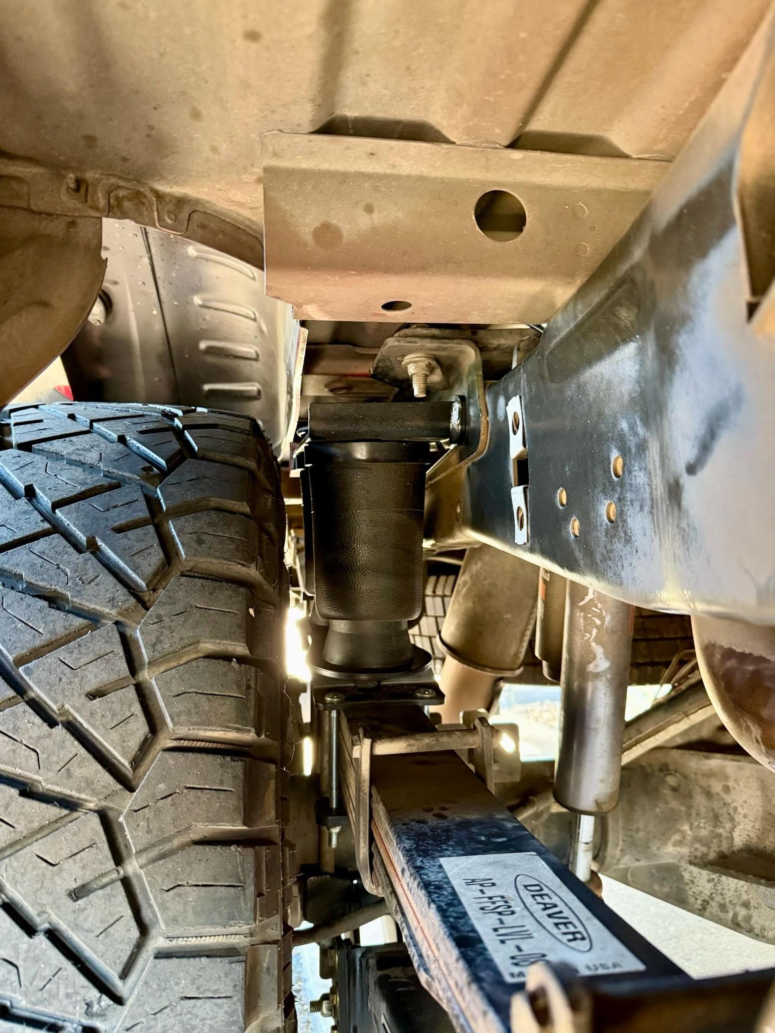 A close up of the underside of a truck with a tire.