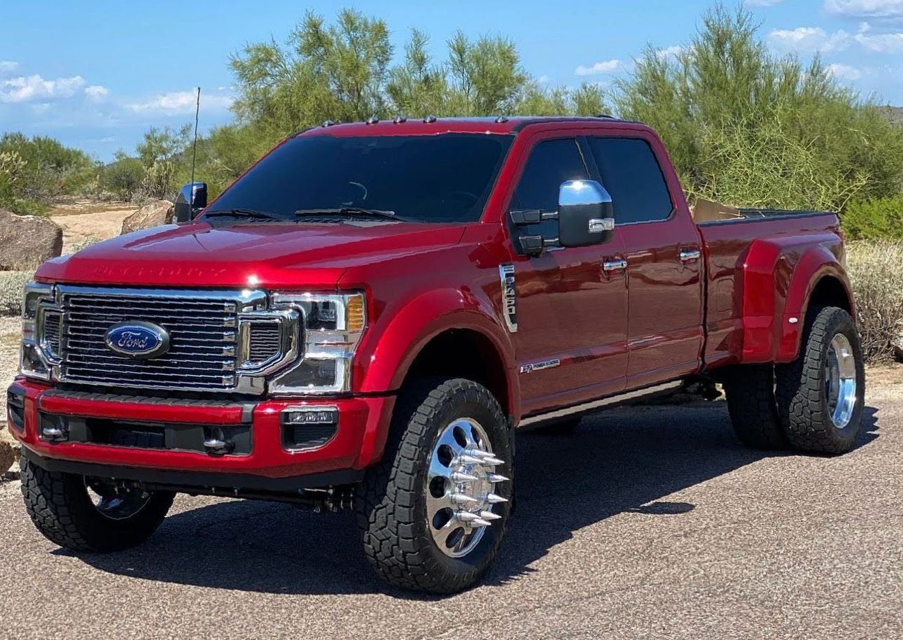 A red ford truck is parked on a dirt road.