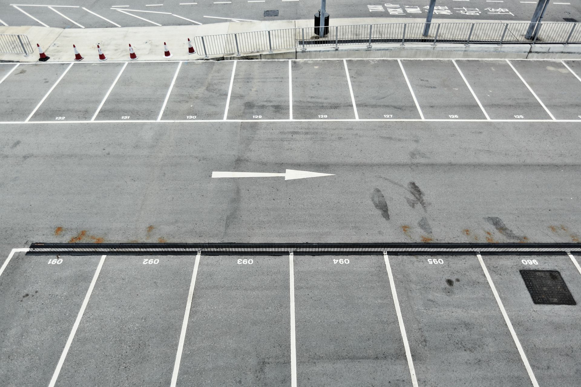 Empty asphalt parking lot with white painted lines and directional arrow.
