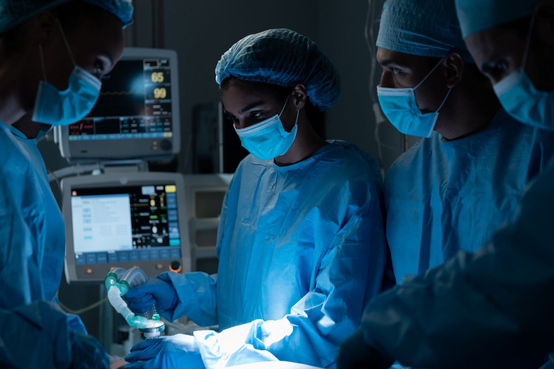 Medical team in scrubs and masks working in a brightly lit operating room.