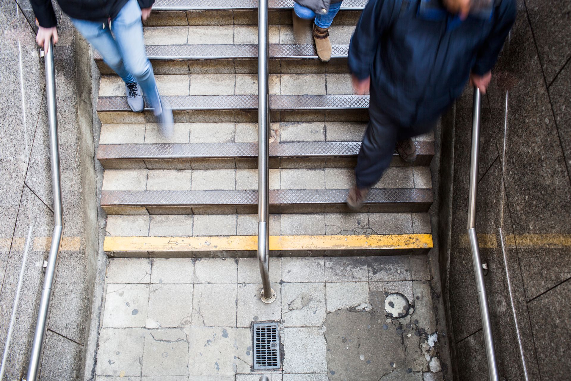 People walking down a metal staircase with handrails in an urban setting.