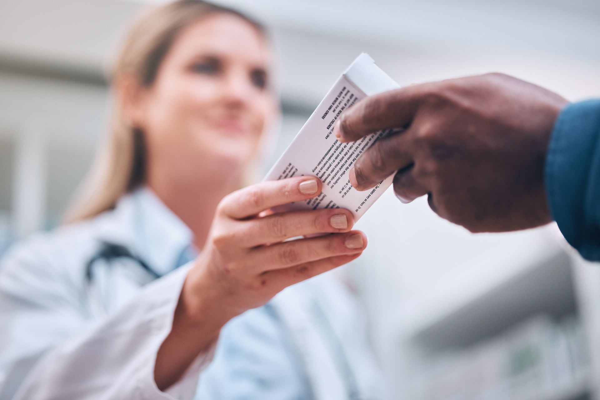 Pharmacist handing medication box to a person in a pharmacy.
