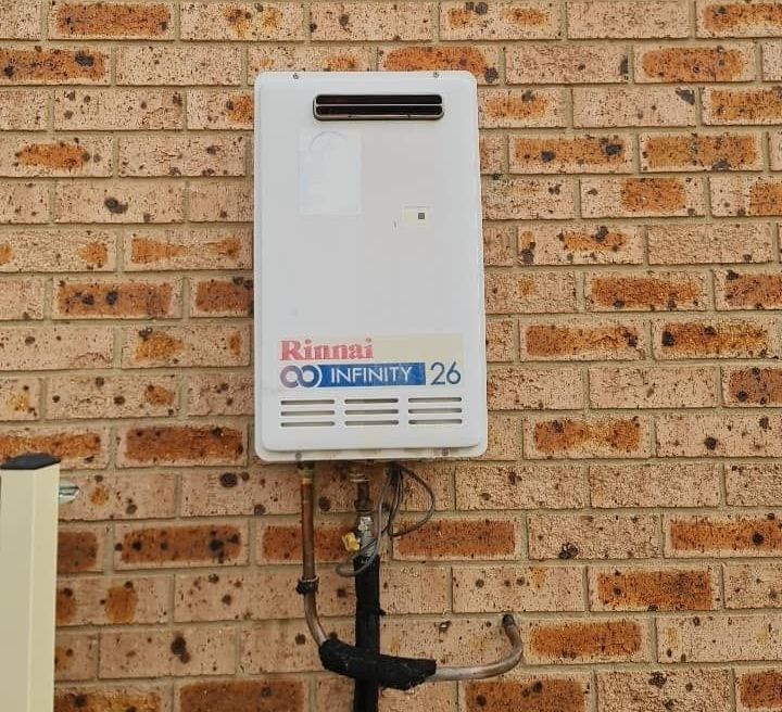 A Rinnai Water Heater Is Mounted To A Brick Wall —  RAW Plumbing & Gasfitting In Pearce, ACT