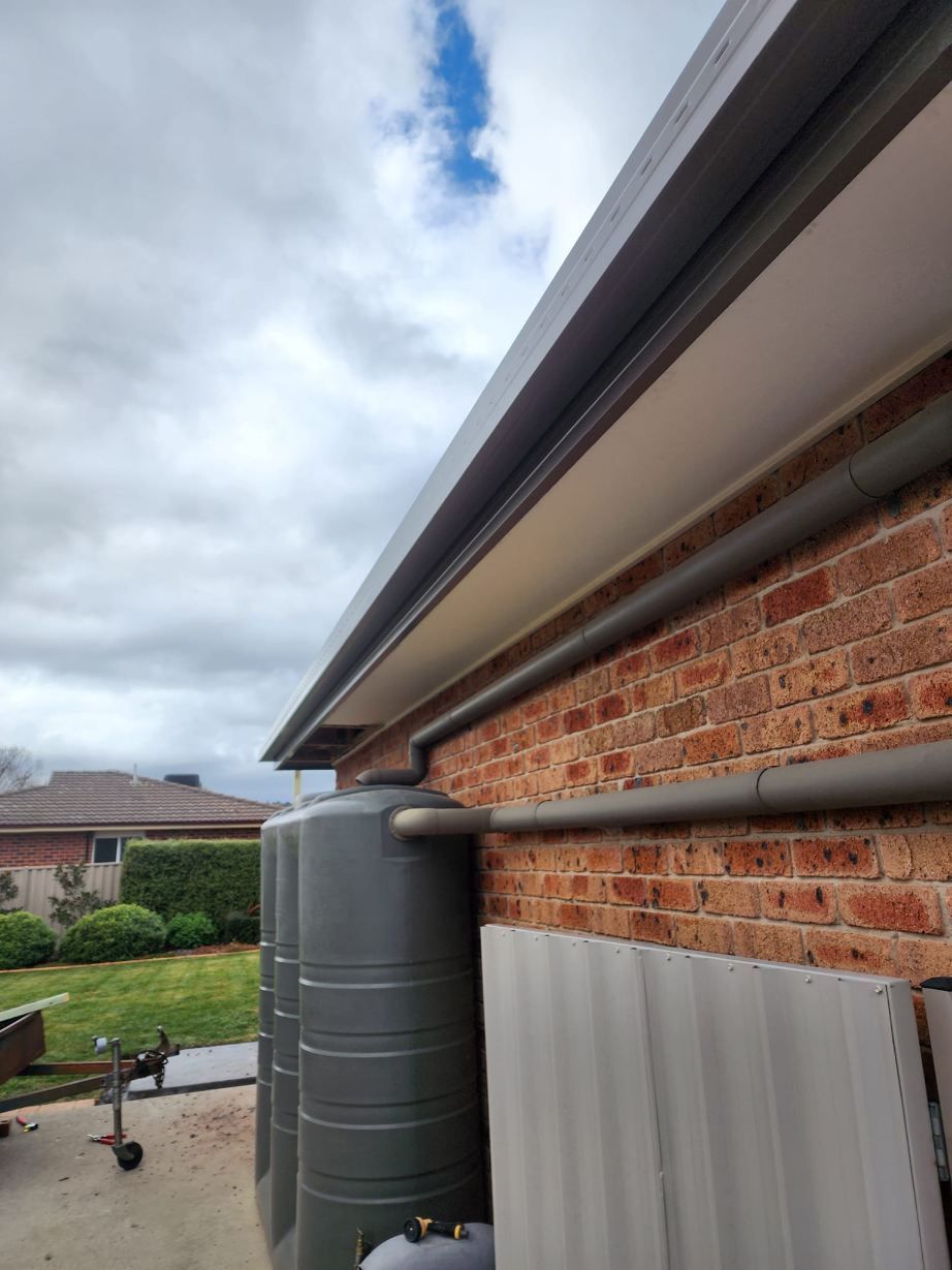 A Brick House With Two Water Tanks On The Side Of It —  RAW Plumbing & Gasfitting In Pearce, ACT