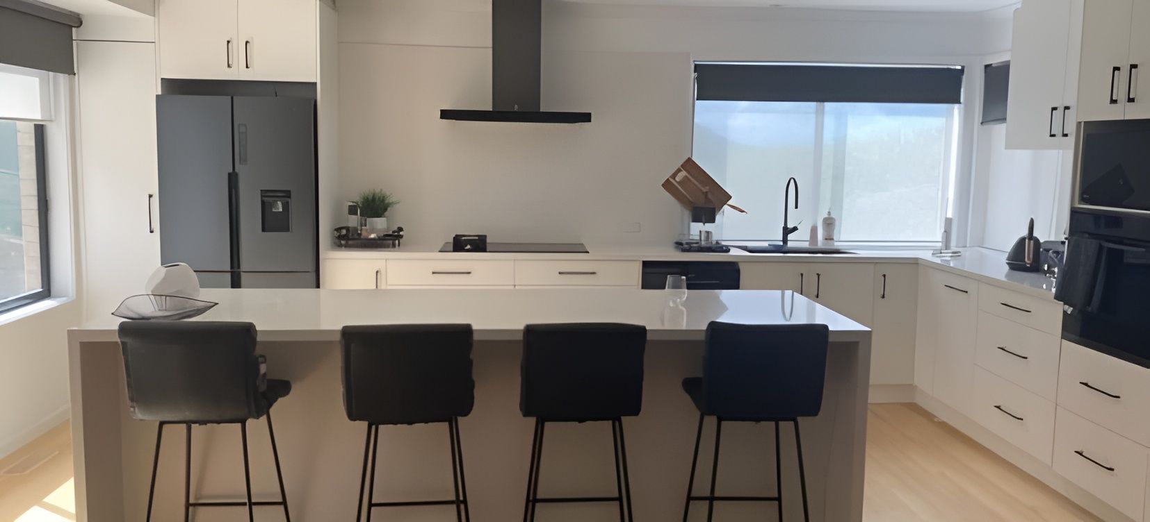 A Kitchen With White Cabinets , Black Stools And A Large Island — RAW Plumbing & Gasfitting In Pearce, ACT