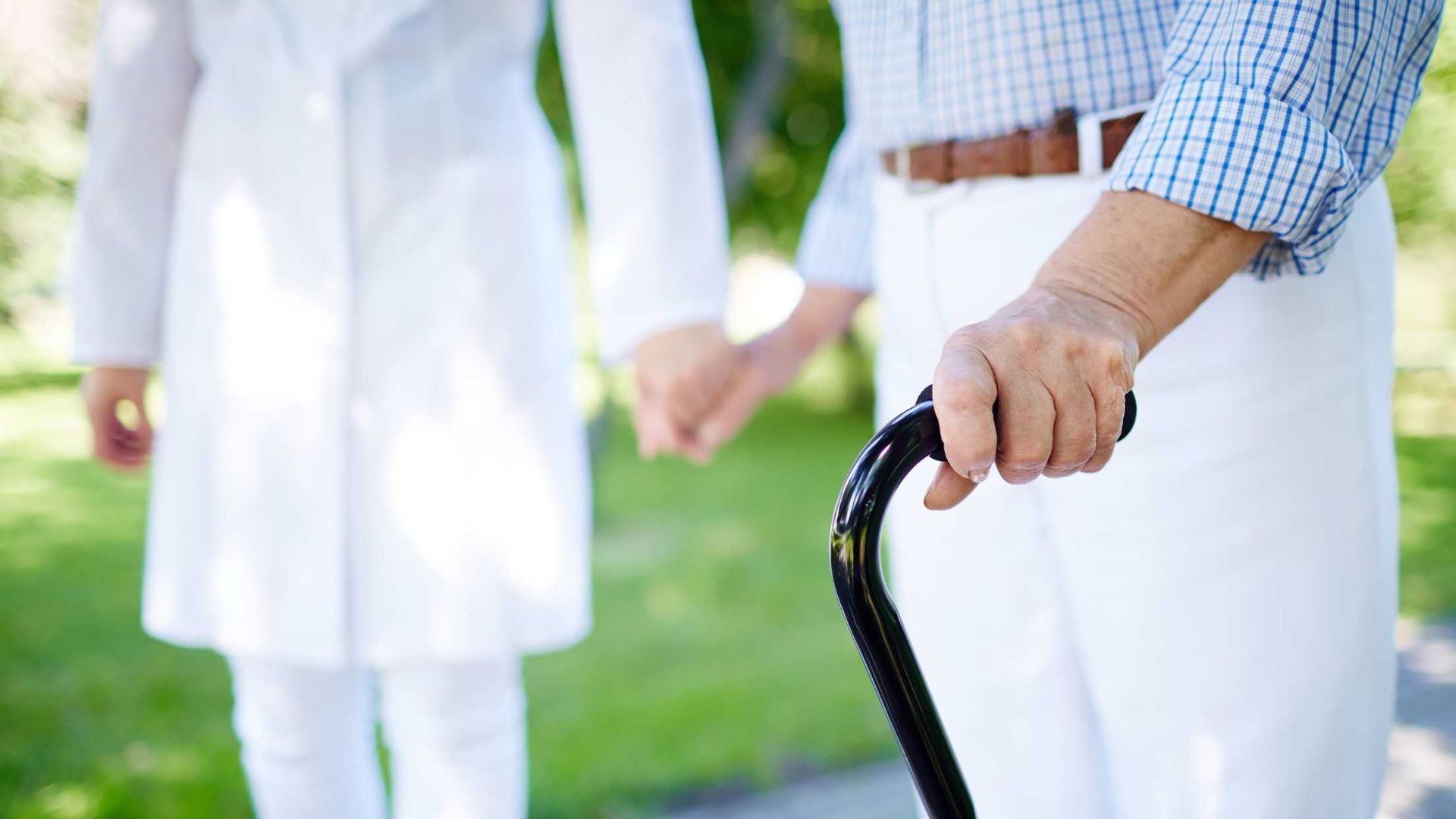 A man is holding a cane and a woman is holding his hand.