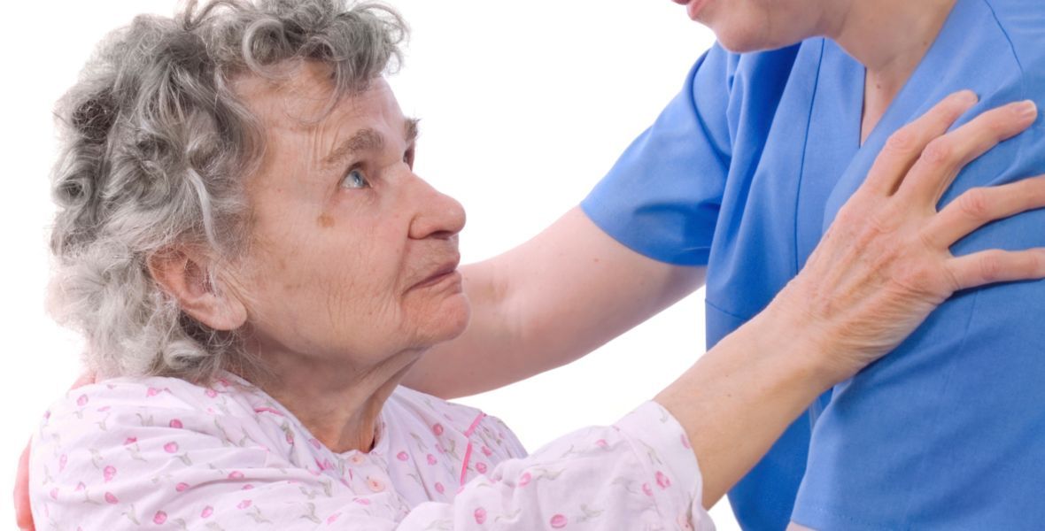 A man is helping an elderly woman with a cane.