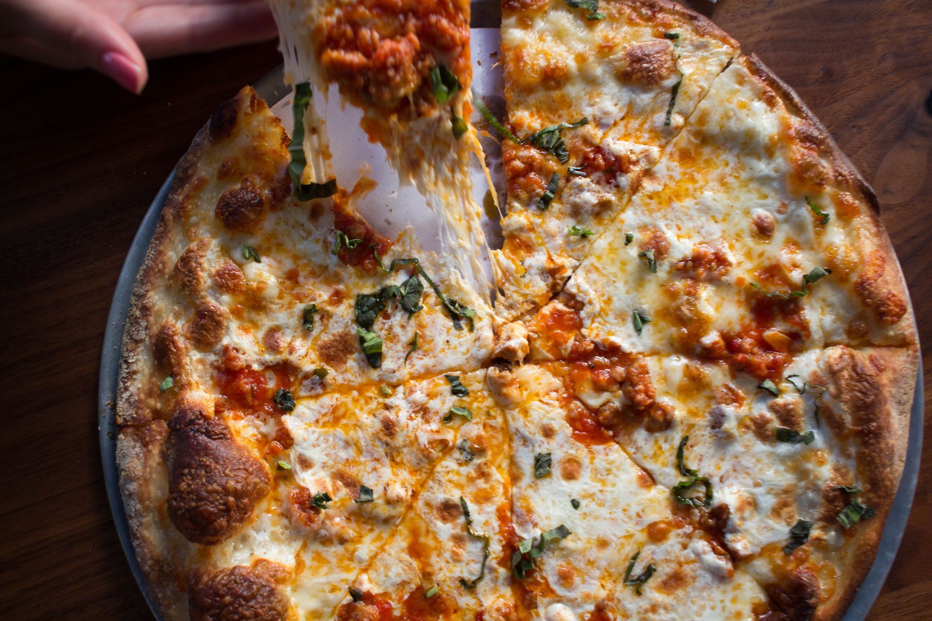 Margherita pizza with melted mozzarella, tomato sauce, and basil leaves on a wooden board