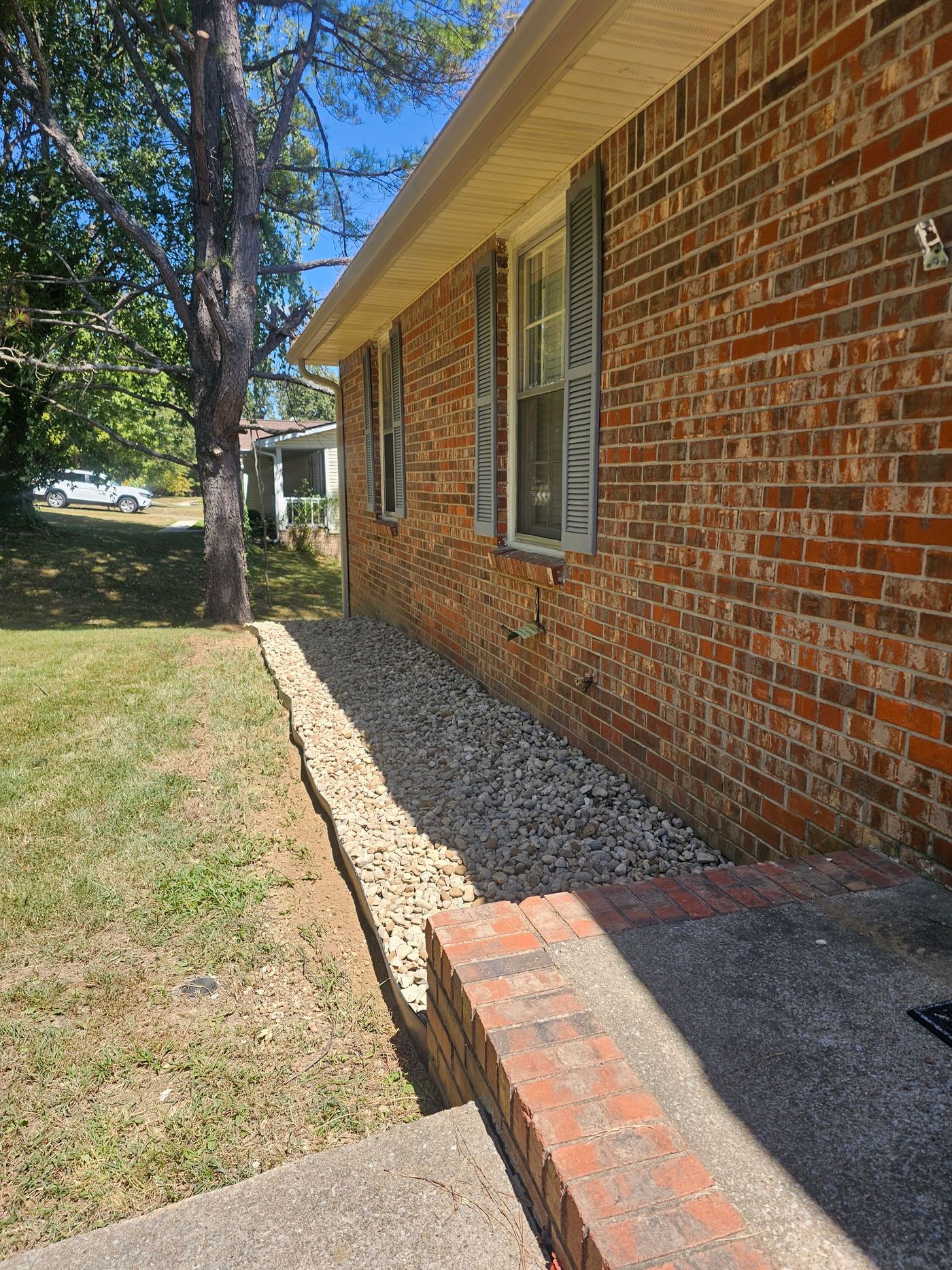 Brick house exterior with gray stone landscaping. A brick walkway leads to the front door.