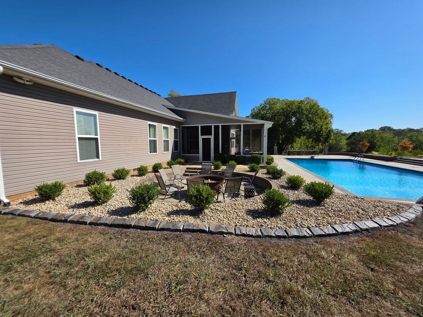 House exterior with pool, landscaping, and fire pit on a sunny day.