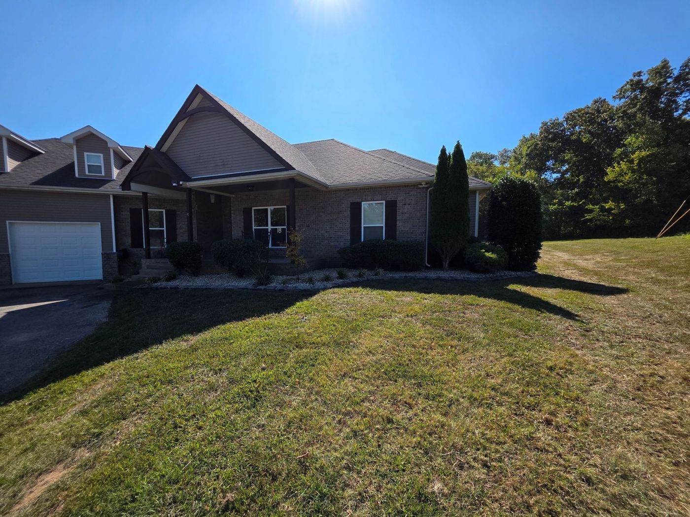 A one-story brick house on a sunny day, with a well-kept lawn and a clear blue sky.