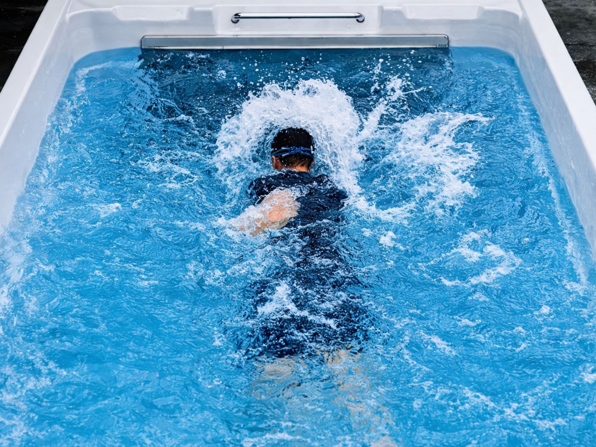 Person swimming against a powerful counter-current in an above-ground endless pool swim spa