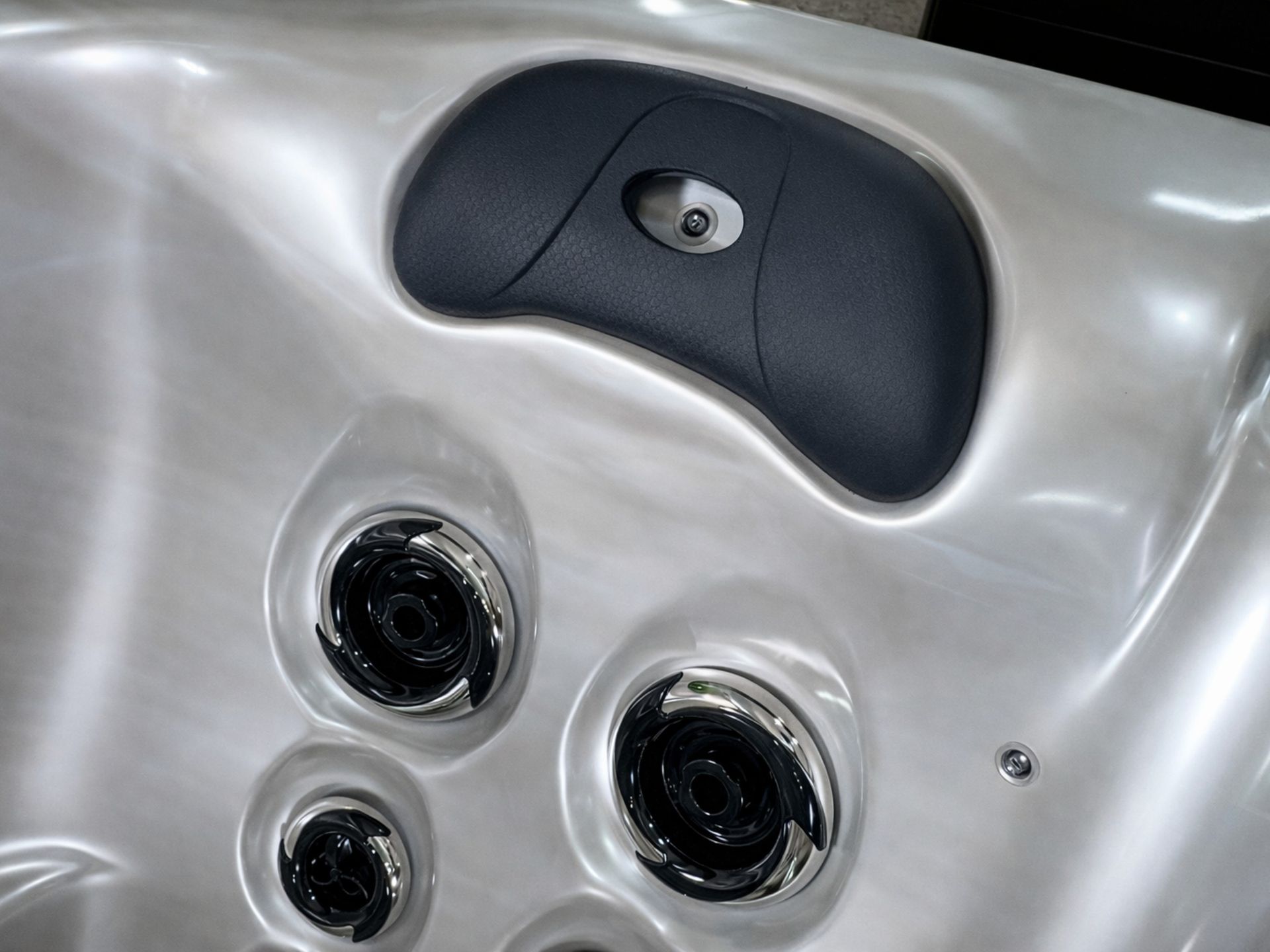 Black ergonomic headrest pillow inside a hot tub with massage jets positioned below