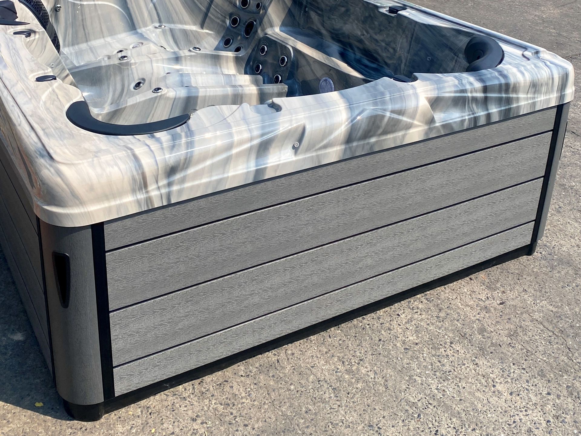 ภาพอ่างน้ำร้อนตกแต่งรอบตัวด้วยไม้เทียมสังเคราะห์สีเทา ดีไซน์เรียบหรูสไตล์โมเดิร์น วัสดุทนแดด ทนฝน และความชื้น ไม่บิดงอหรือผุกร่อนง่าย เหมาะสำหรับติดตั้งภายนอกอาคาร เพิ่มความสวยงามและความทนทานในการใช้งานระยะยาว