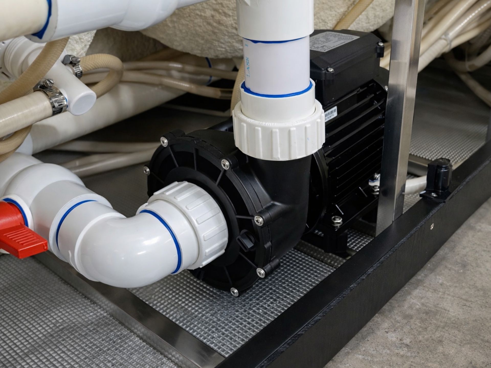 Hot tub pump system with PVC plumbing and control valve installed under spa base