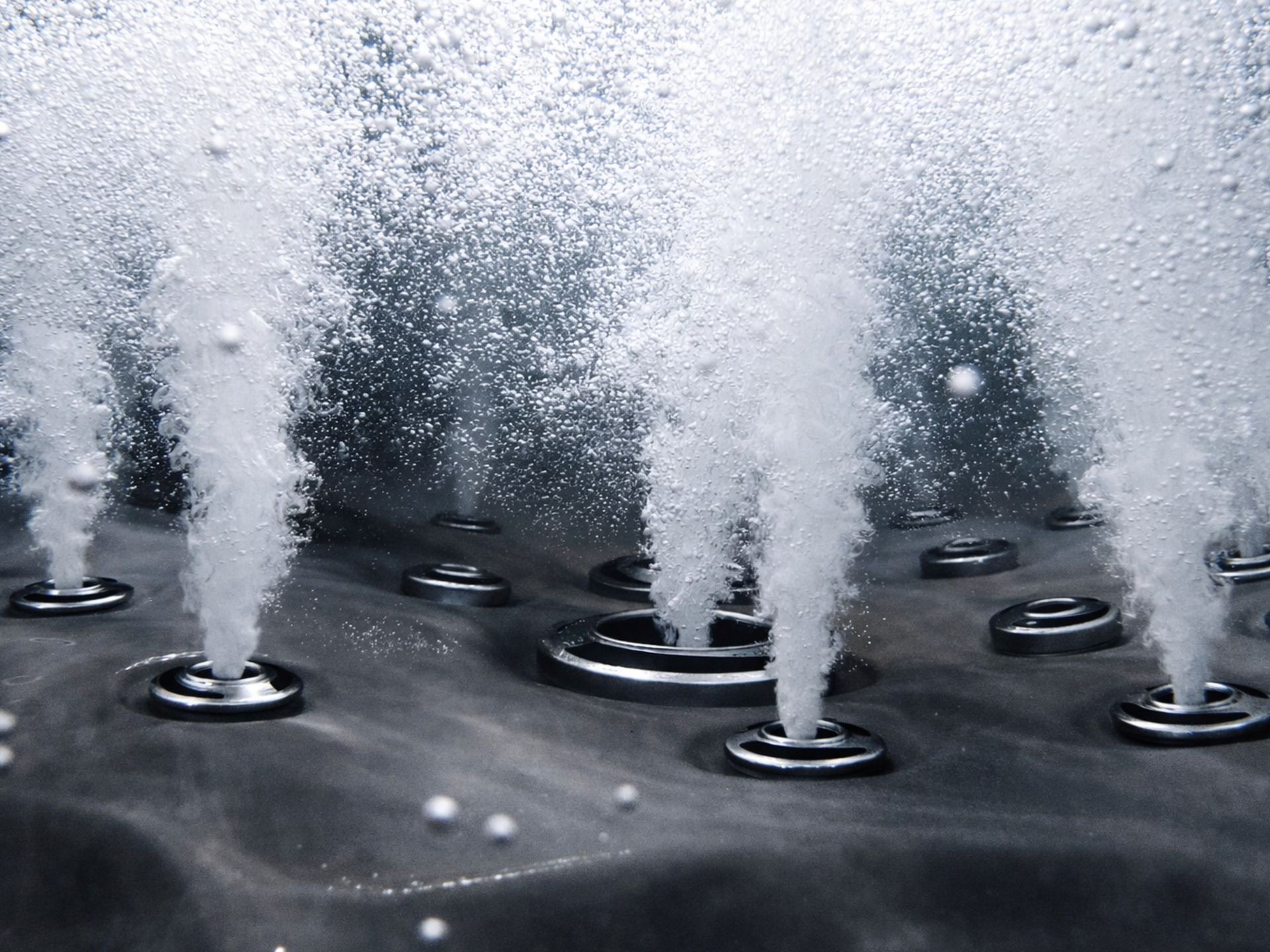 ภาพระยะใกล้ระบบเจ็ตนวดในอ่างน้ำร้อน แสดงหัวเจ็ตแรงดันสูงปล่อยสายน้ำและฟองอากาศจำนวนมาก เพื่อการนวดกล้ามเนื้ออย่างล้ำลึกในอ่างสปากลางแจ้ง