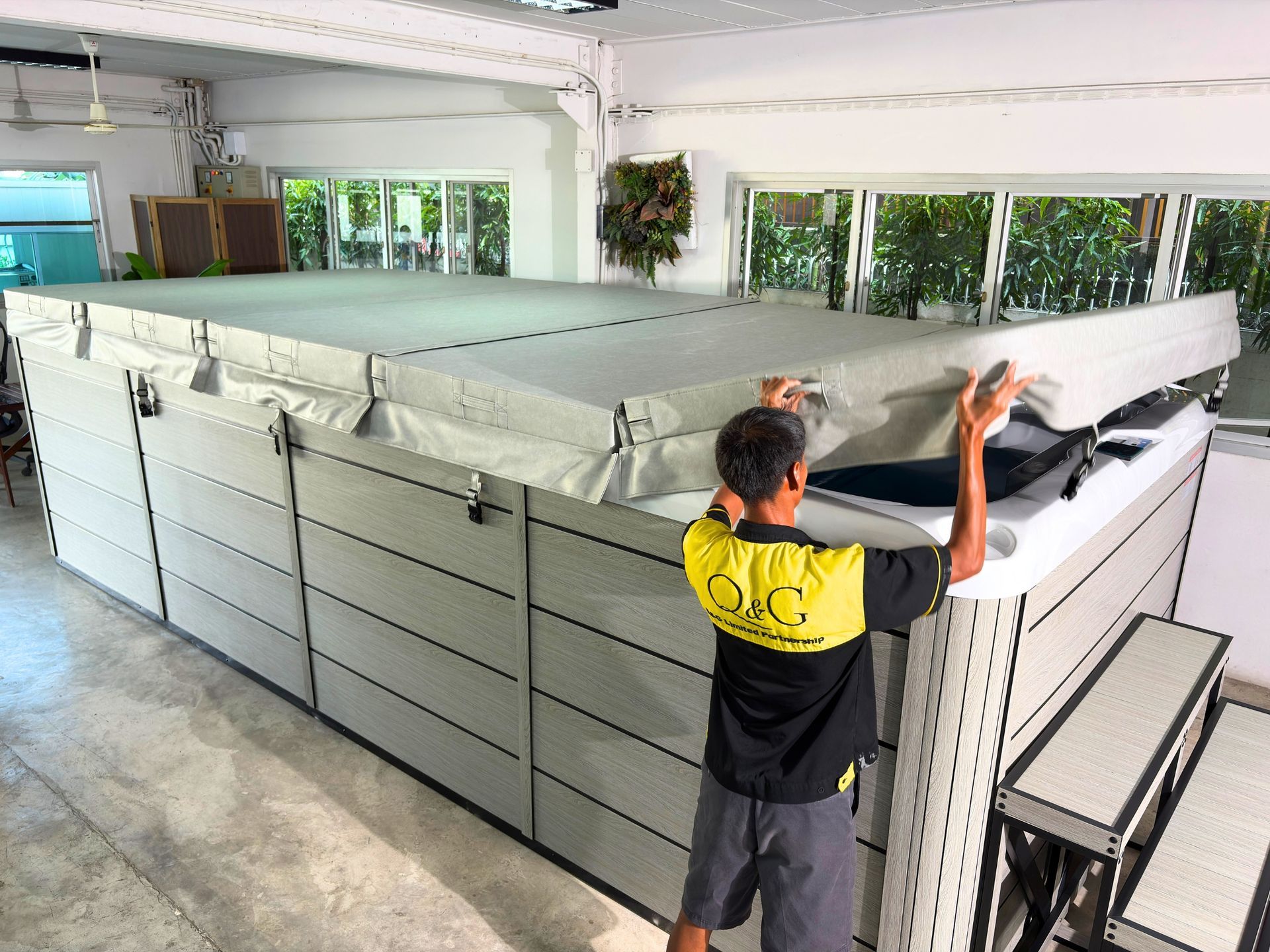 Technician opening the insulated hard cover of a swim spa with composite cabinet and galvanized steel frame.