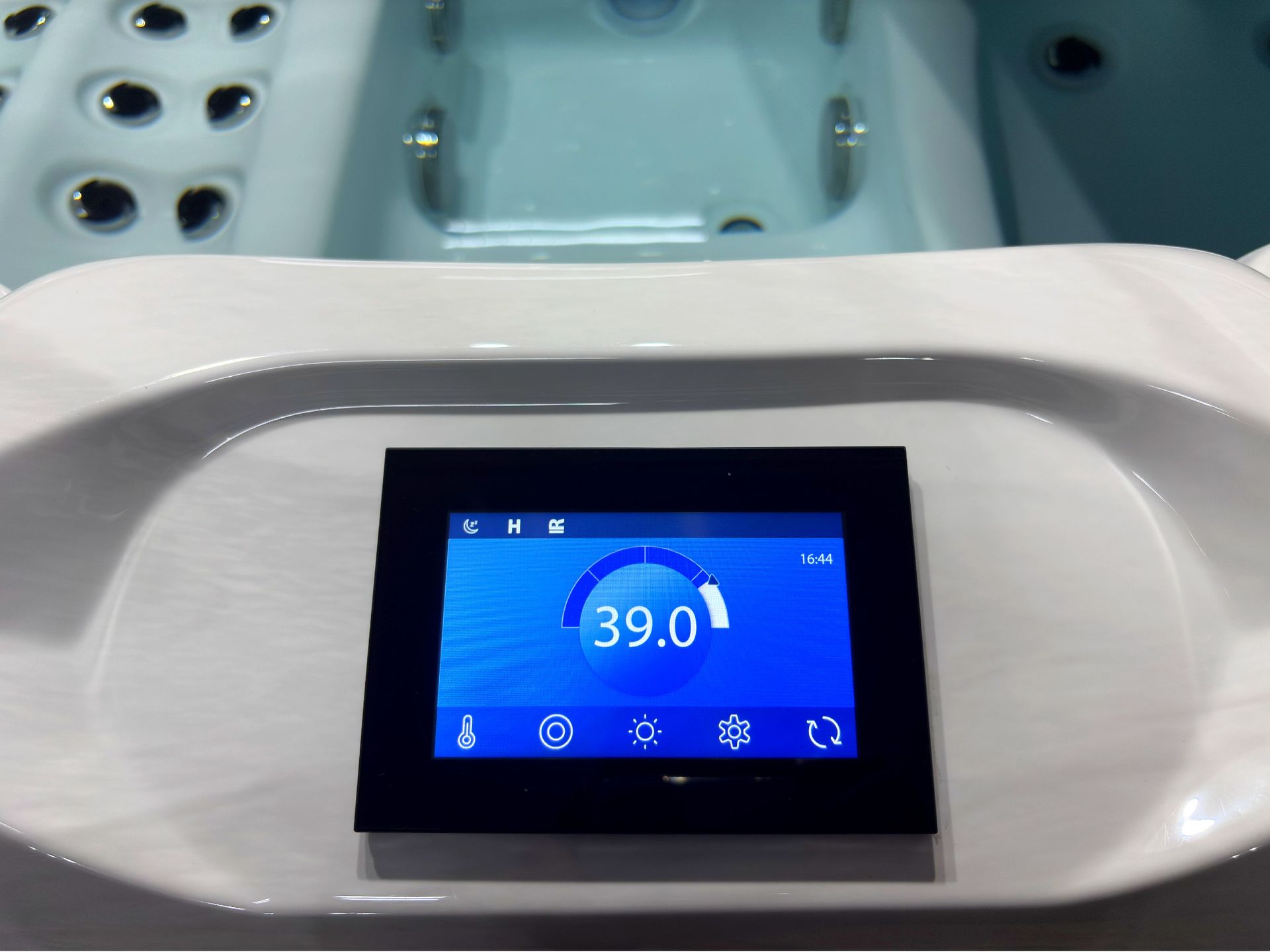 Outdoor hot tub touchscreen control panel showing water temperature and system settings
