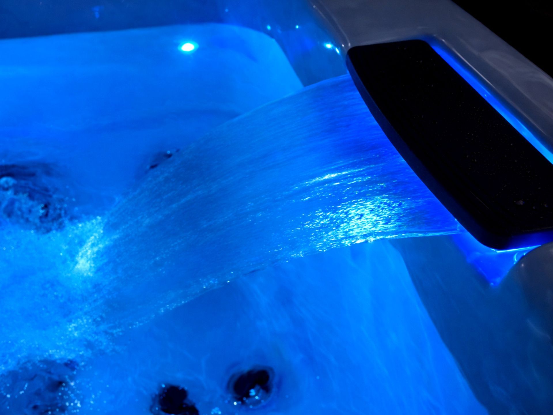 Close-up of hot tub waterfall feature with blue LED lighting, creating a relaxing luxury spa ambiance for outdoor jacuzzi and resort installations in Thailand