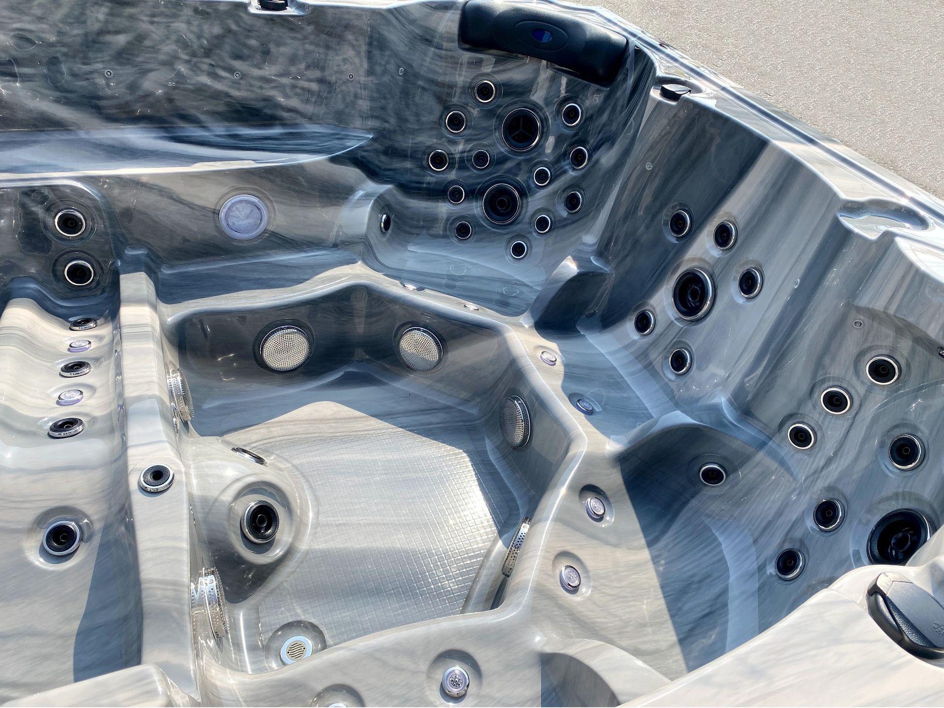 ภาพภายในอ่างน้ำร้อนแสดงพื้นผิววัสดุอะคริลิคโทนสีเทาลายหินอ่อน ผิวเรียบเนียน แข็งแรง ทนทานต่อความร้อนและความชื้น พร้อมดีไซน์รองรับสรีระและติดตั้งระบบเจ็ตนวดอย่างลงตัว