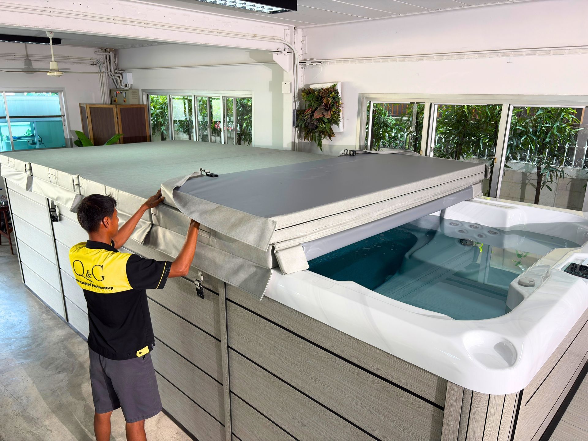 Swim spa with folded insulated hard cover, showcasing spacious swim area and sturdy galvanized steel frame support.
