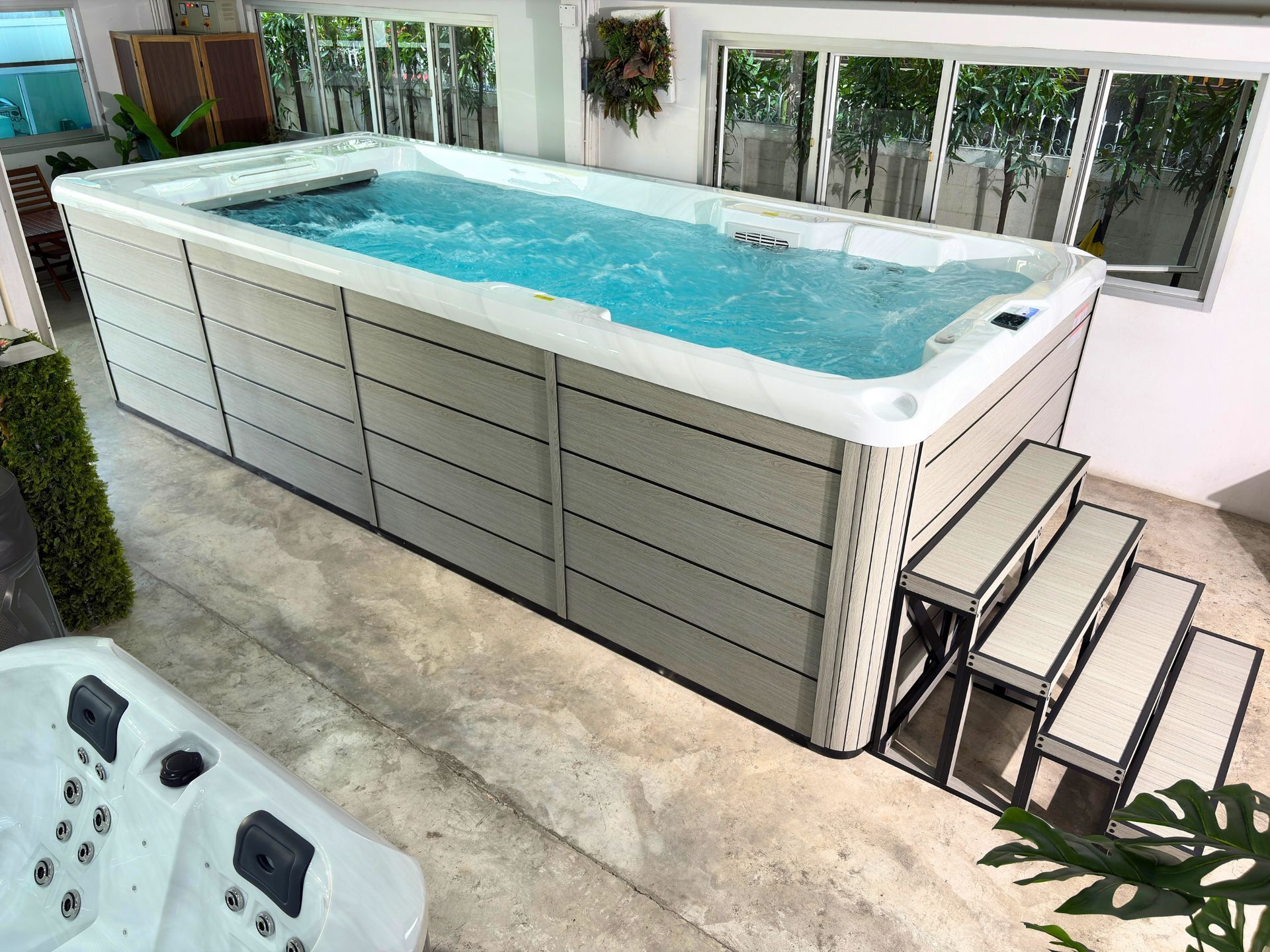 Swim spa filled with water and running counter-current swim system, supported by a durable galvanized steel frame.