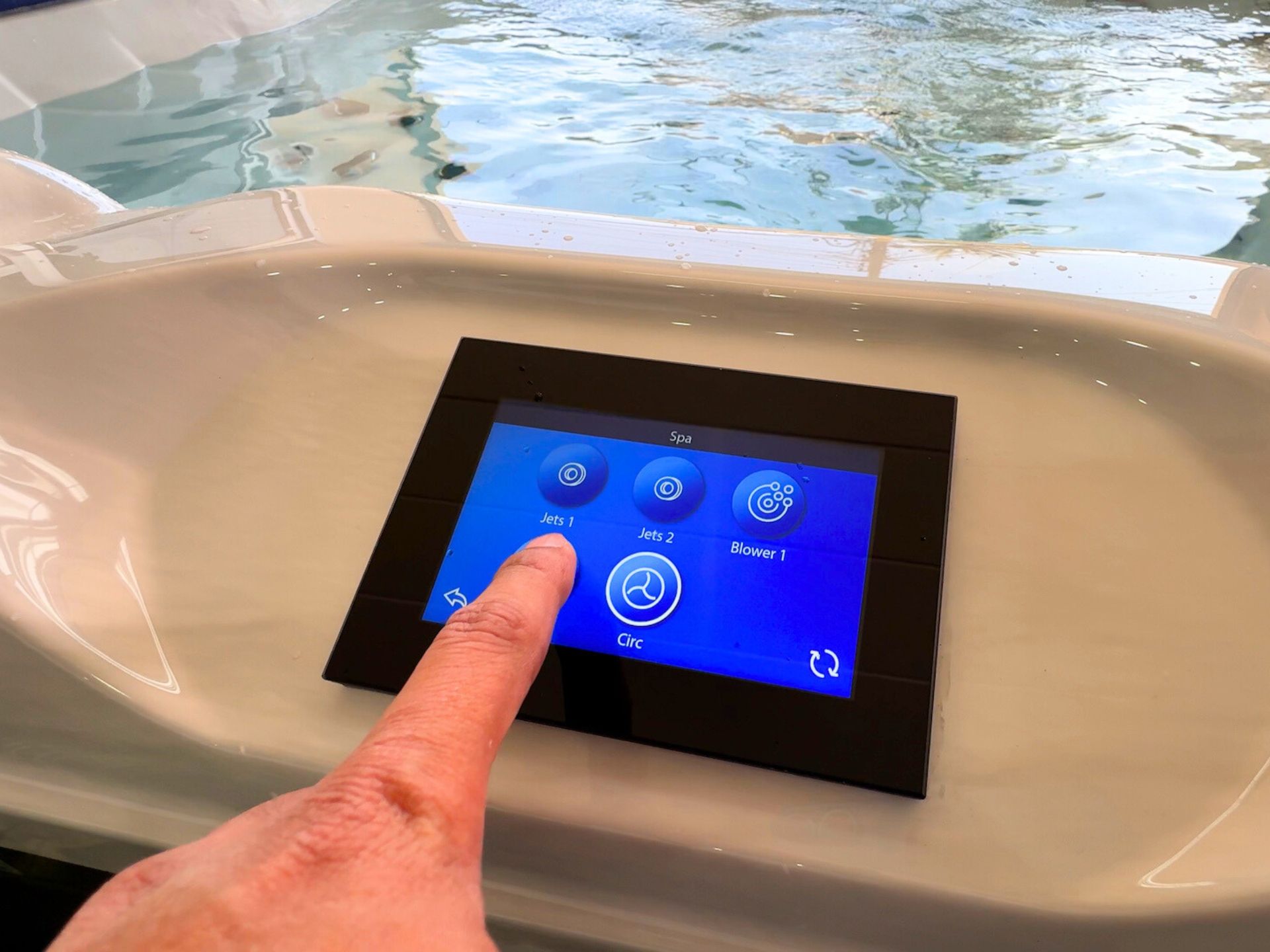 Image of a USA touchscreen control panel for hot tub operation, showing finger interaction to activate hydrotherapy jets and blower functions. The smart spa control system provides easy access to pump control, water circulation, and massage settings, ideal for residential homes, villas, and resort spa installations in Thailand.