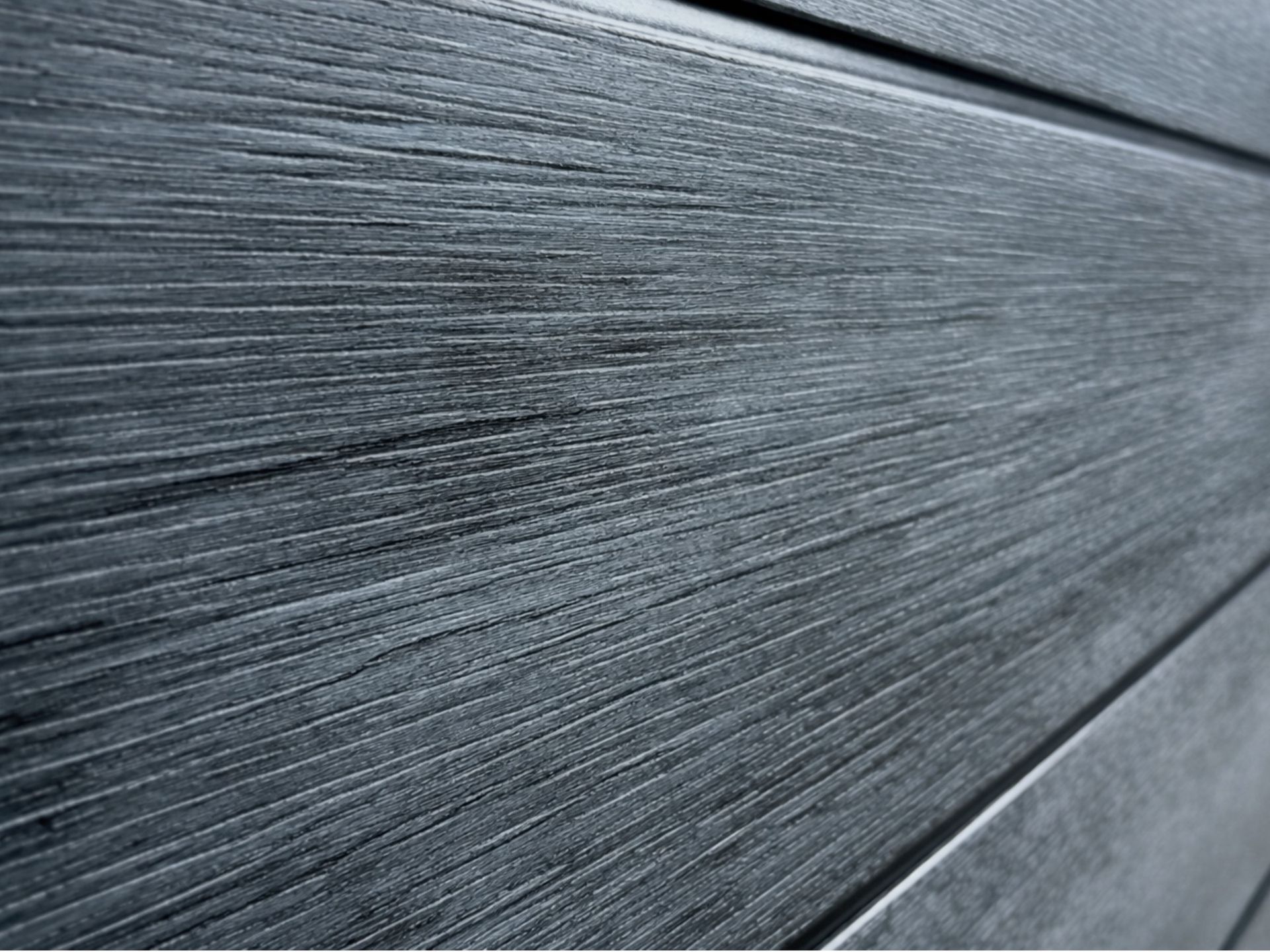 Dark grey composite wood cabinet panel surrounding an outdoor hot tub with textured wood grain finish