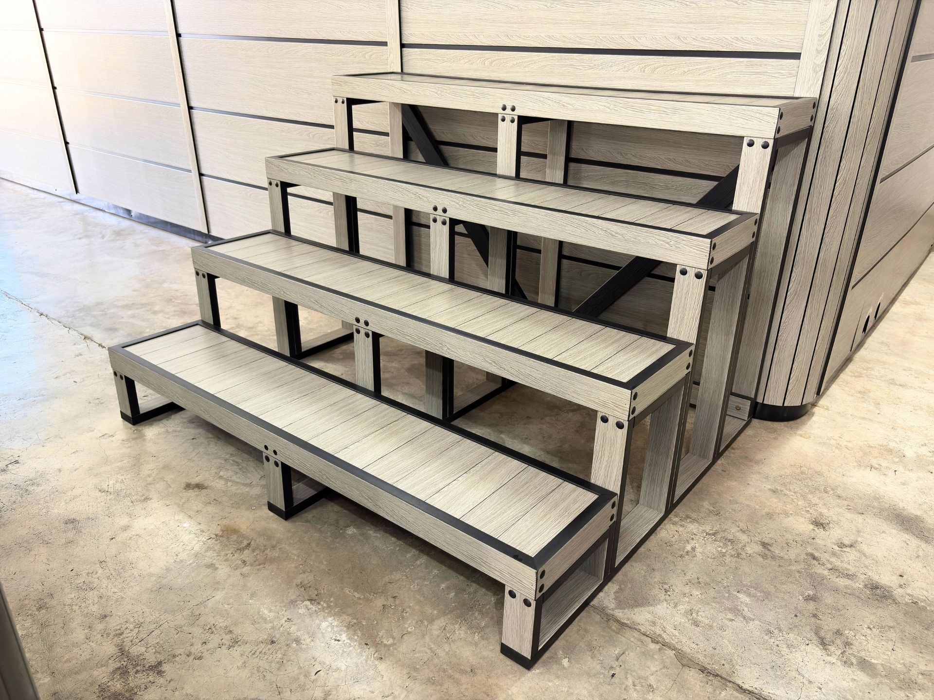 Four-tier hot tub steps made of composite material positioned against a matching spa cabinet.