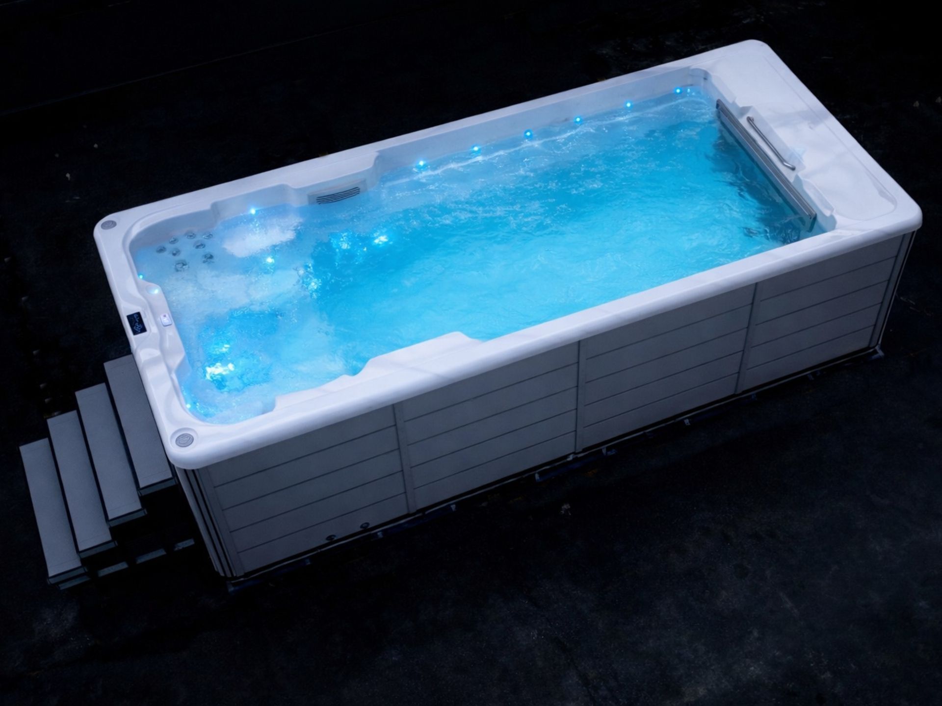 Ultimate 16 above-ground swim spa with LED lighting at night, showing full swimming and relaxation area