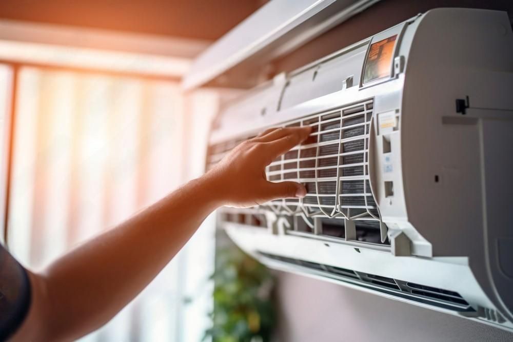 A person is cleaning the filter of an air conditioner.