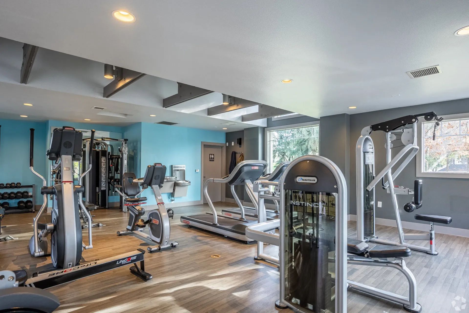 Indoor community gym with treadmills, stationary bikes, and weight machines.