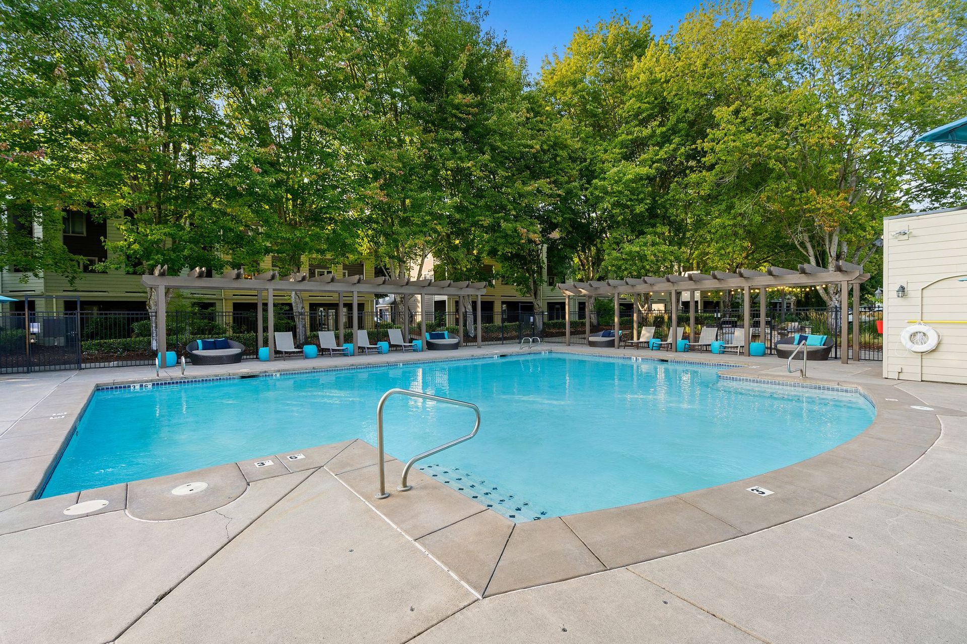 Outdoor communal pool with lounge chairs and modern apartment buildings surrounding.