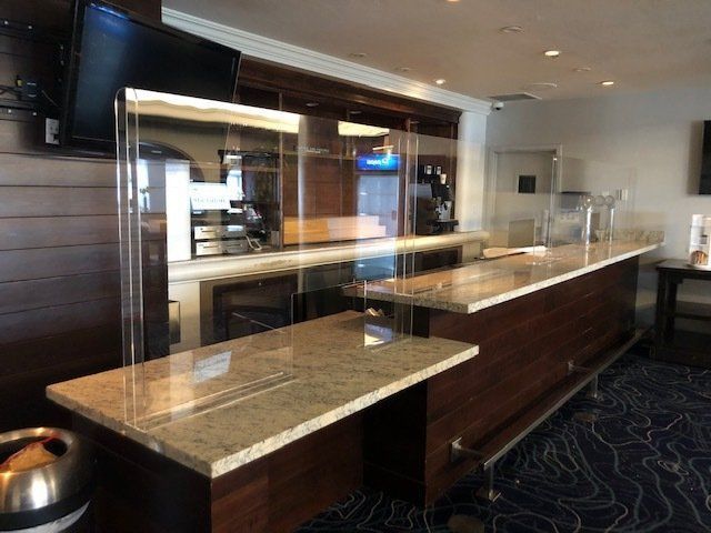 A long counter in a restaurant with a clear acrylic barrier.