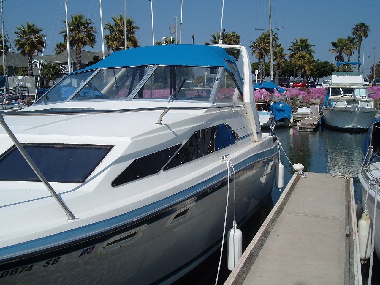 A boat with a blue canopy is docked at a marina