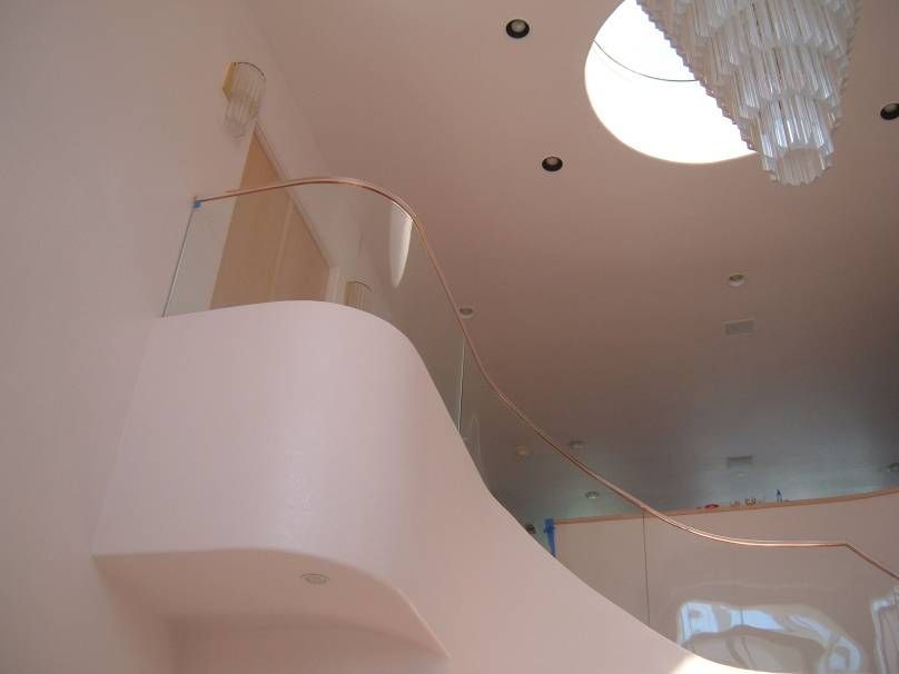 A staircase with a glass railing and a chandelier hanging from the ceiling