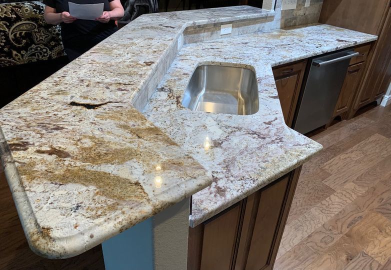 A kitchen with granite counter tops and a stainless steel sink.