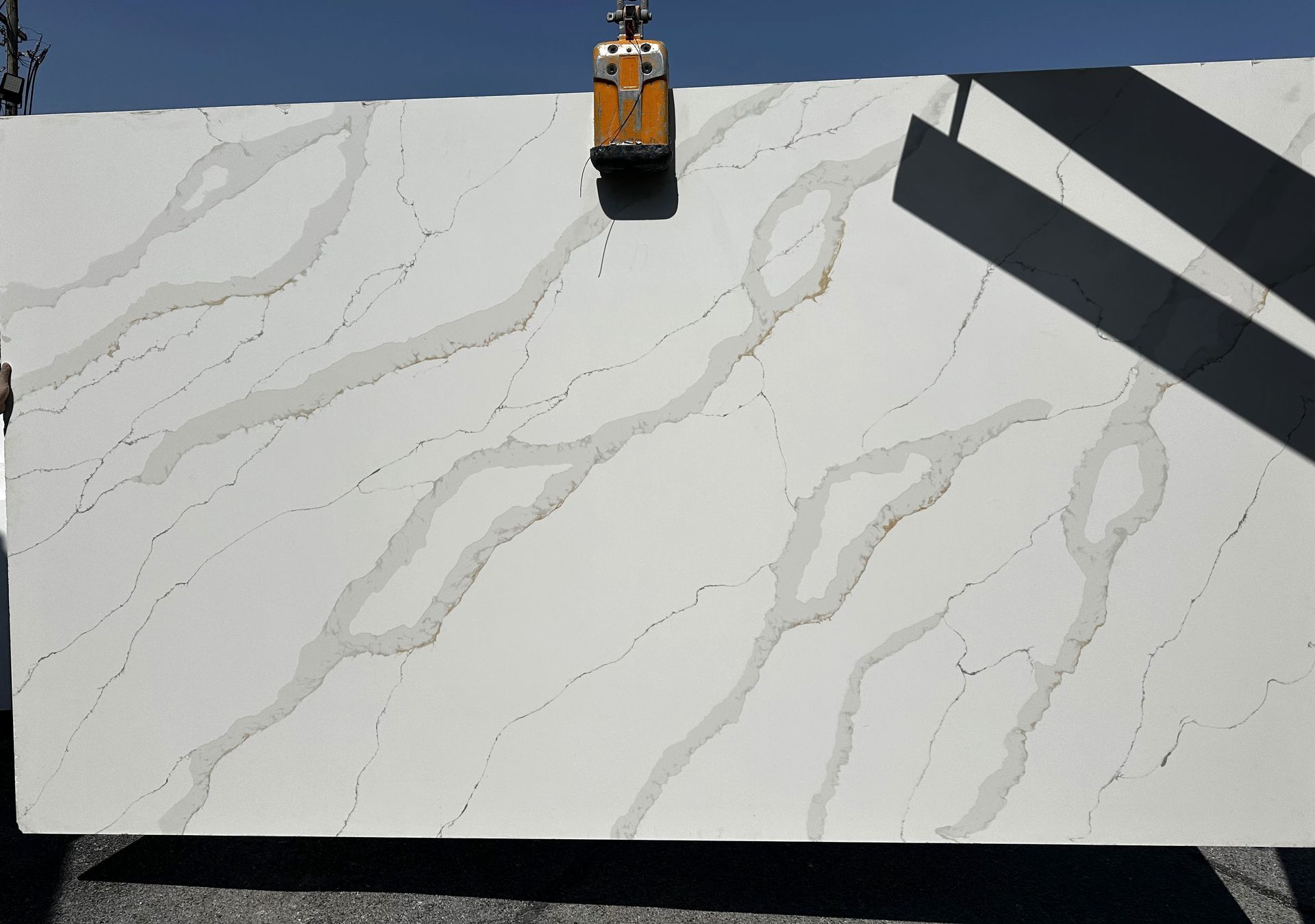 A large white granite slab is being lifted by a crane.